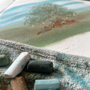 soft pastels sitting on a microfiber cloth in front of a piece of artwork